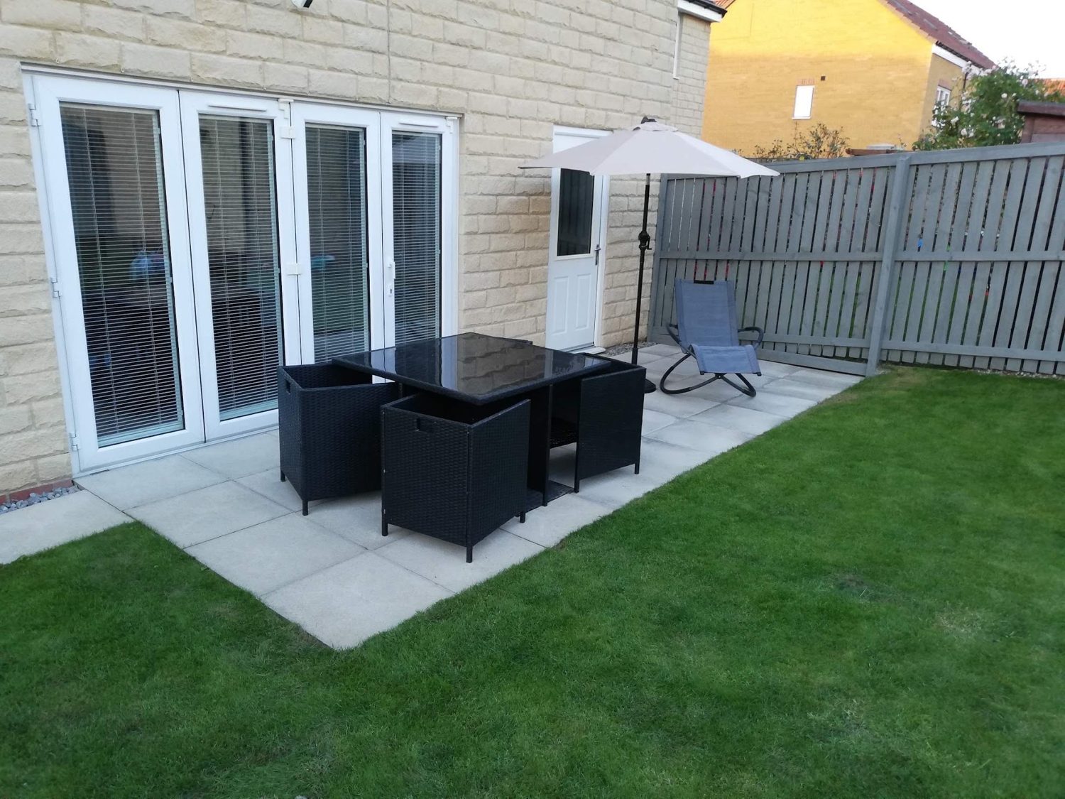 A patio with a table set, folding doors and a fresh lawn