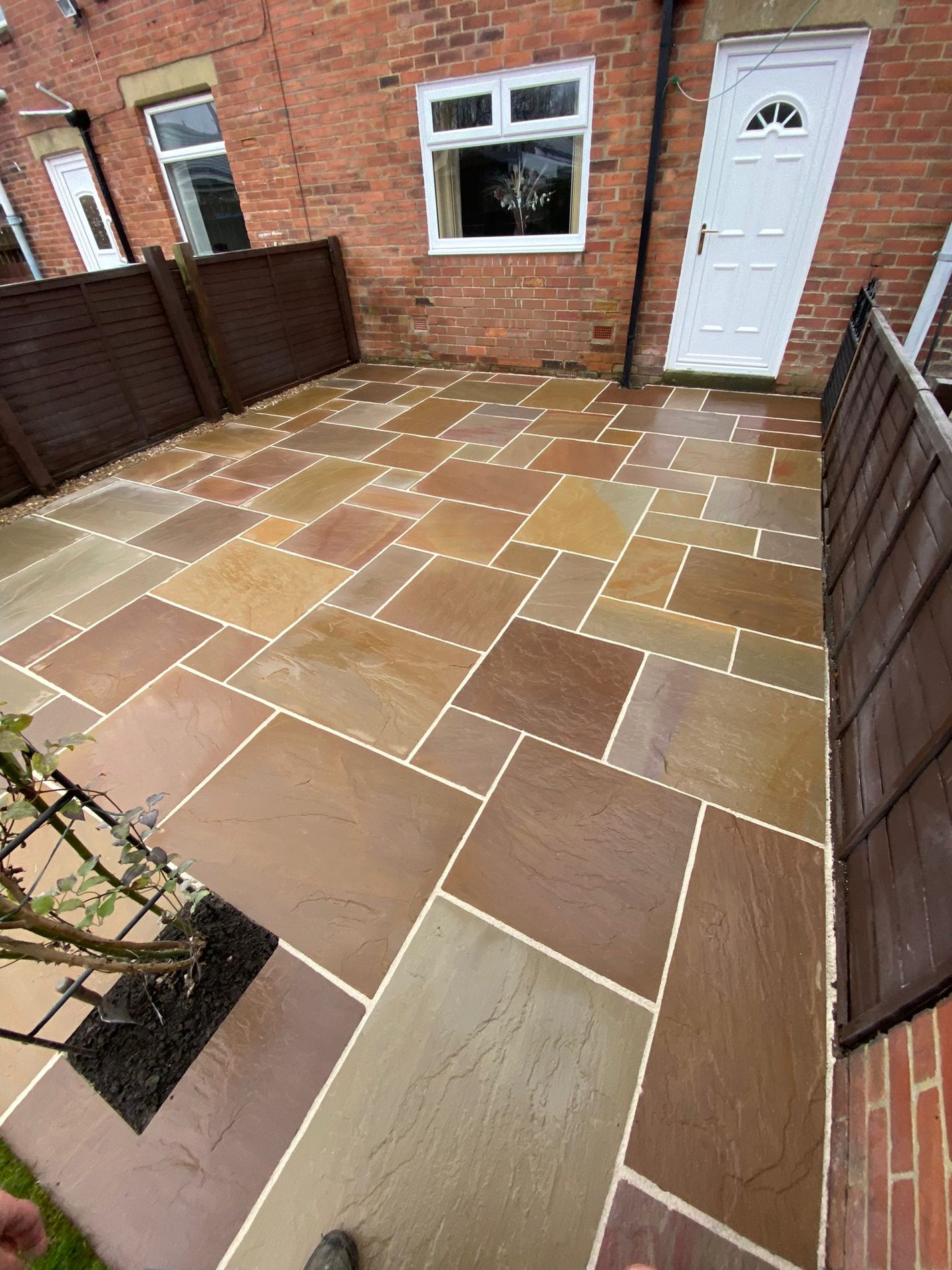 A sandstone patio laid in a random pattern in a back yard