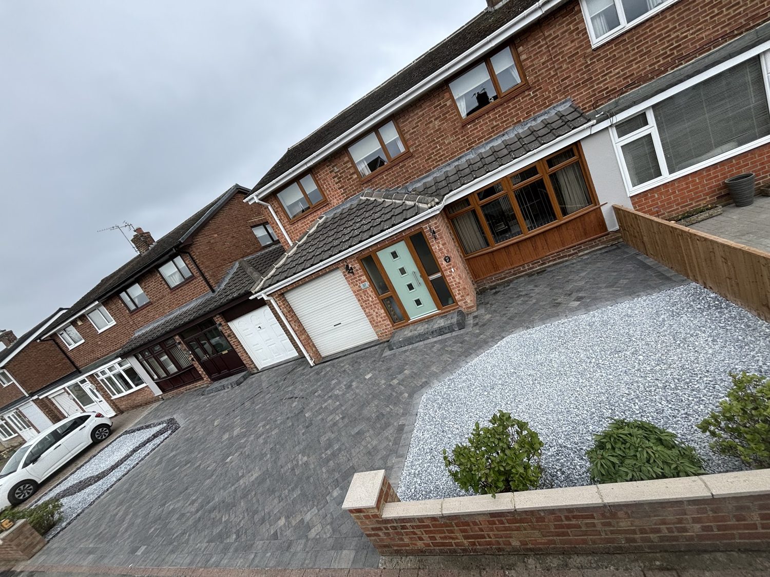 A new block-paved driveway with a pale gravel bed in front of a semi-detached house