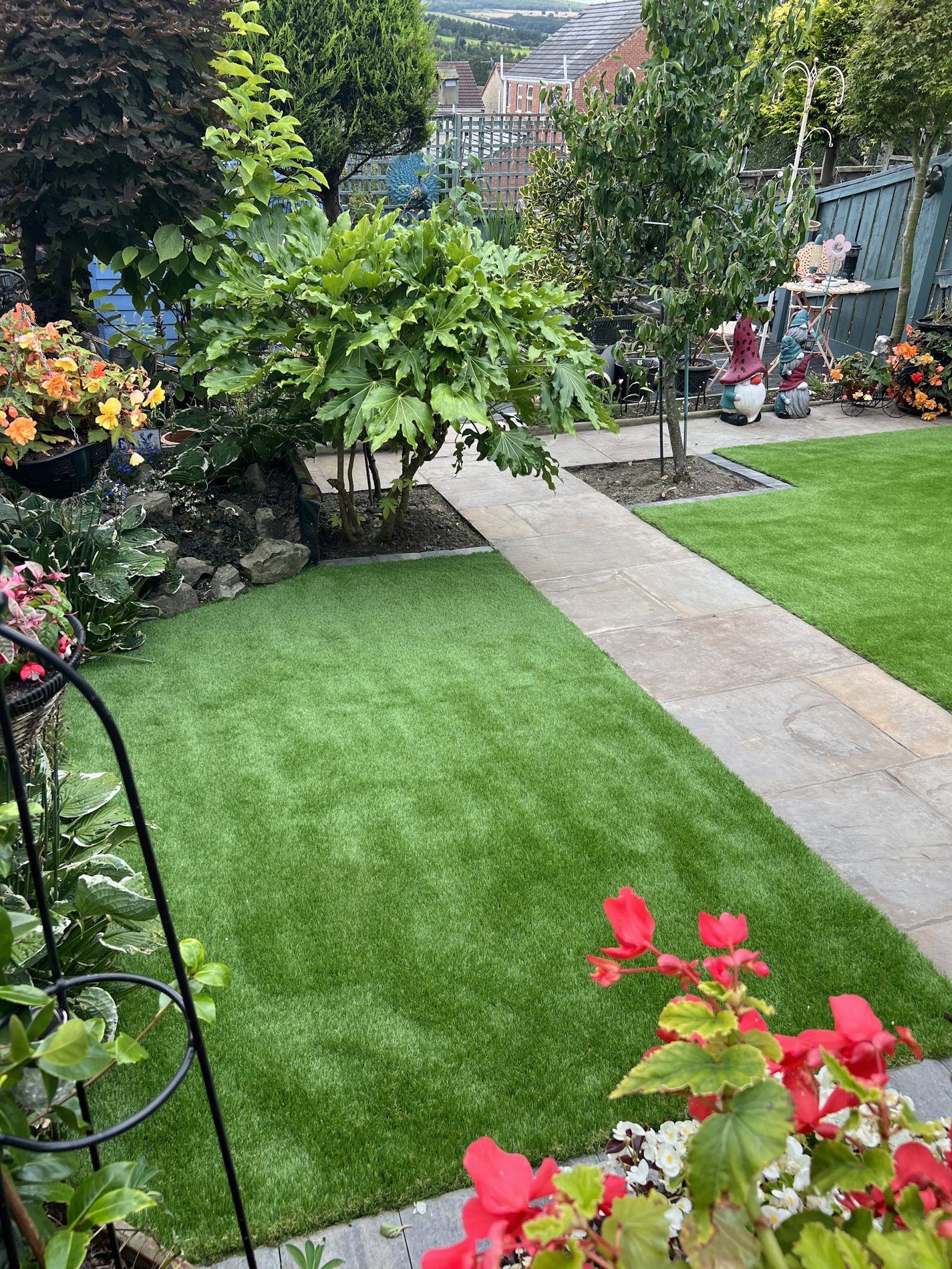 A planted garden with an artificial lawn and a stone path